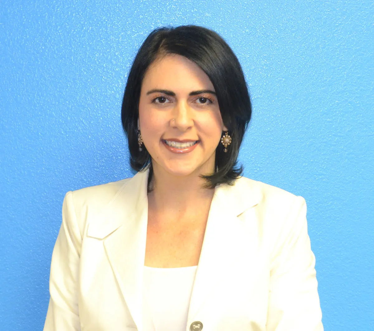 A woman in a white blazer smiles against a vibrant blue background, representing Crown Marketing's digital marketing agency in Las Vegas.| Crown Marketing Digital Marketing Agency Las Vegas