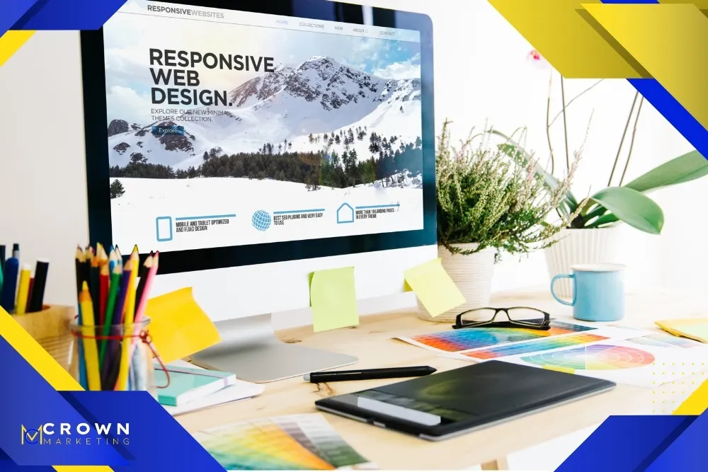 A modern desk setup features a computer displaying "Responsive Web Design" by Crown Marketing, highlighting their digital marketing services alongside colorful design tools and plants.| Crown Marketing Digital Marketing Agency Las Vegas